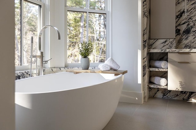 bathroom featuring tile patterned flooring, a soaking tub, and a healthy amount of sunlight