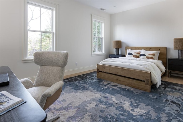 bedroom with visible vents, baseboards, and wood finished floors