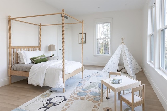 bedroom featuring multiple windows, baseboards, and wood finished floors