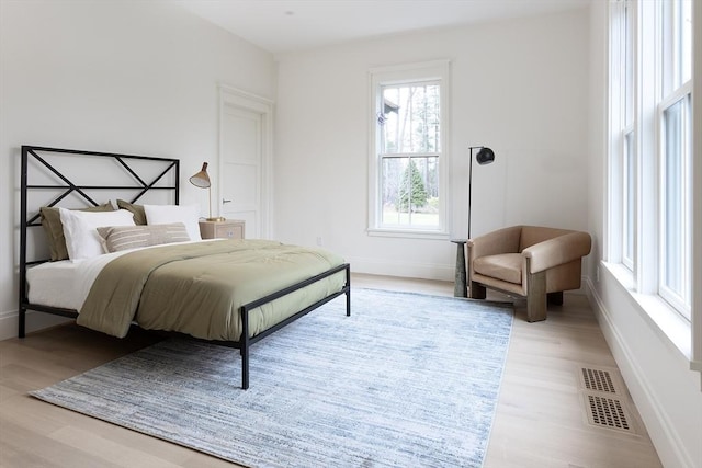 bedroom with wood finished floors, baseboards, and visible vents