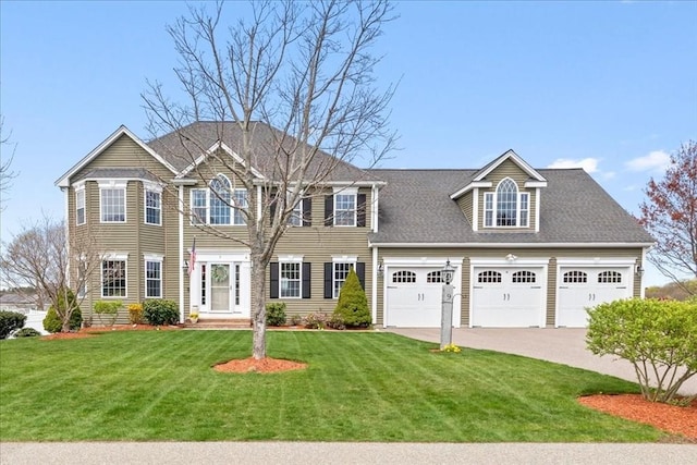 colonial house with an attached garage, driveway, and a front yard