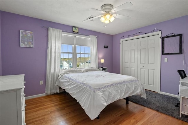 bedroom featuring baseboards, ceiling fan, a closet, and wood finished floors