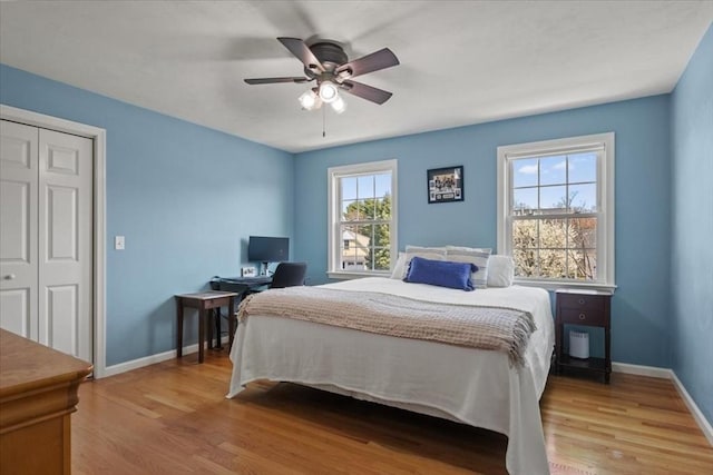 bedroom with baseboards, ceiling fan, and light wood-style flooring