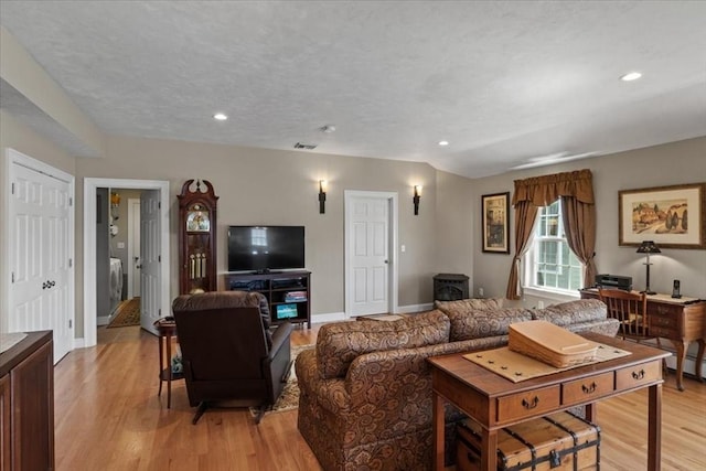 living area with a wood stove, light wood-style flooring, recessed lighting, baseboards, and visible vents