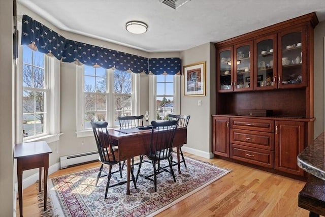 dining area featuring baseboards, a baseboard radiator, light wood-style flooring, and visible vents
