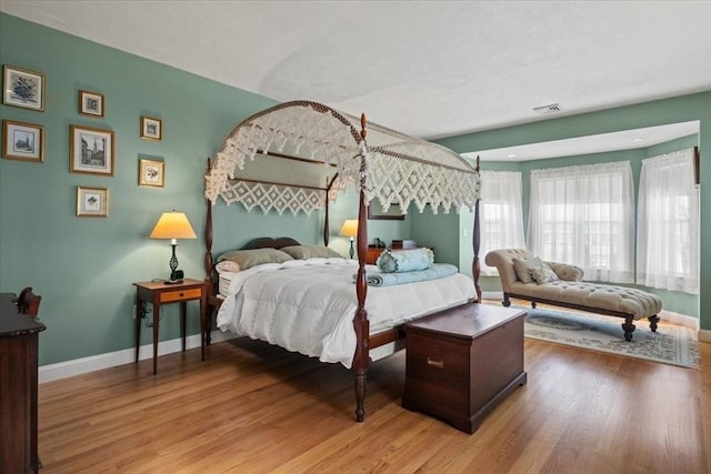 bedroom featuring baseboards, light wood finished floors, and visible vents