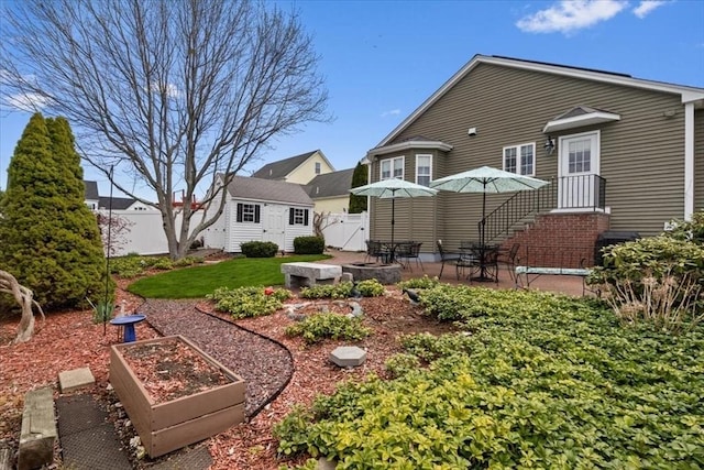 rear view of house with an outbuilding, a fenced backyard, a patio area, and a vegetable garden