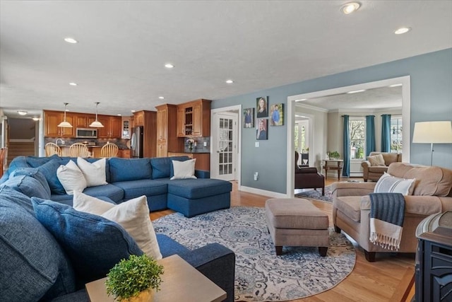living area featuring baseboards, light wood finished floors, and recessed lighting