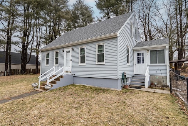 view of front of property with entry steps, a shingled roof, a front yard, and fence