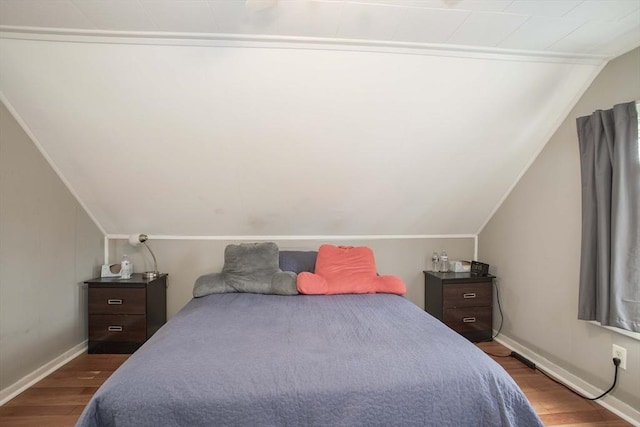 bedroom with baseboards, vaulted ceiling, and wood finished floors