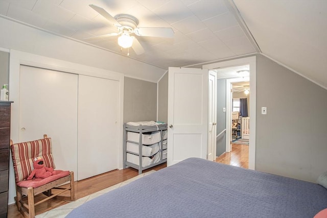 bedroom with light wood-type flooring, a closet, a ceiling fan, and lofted ceiling