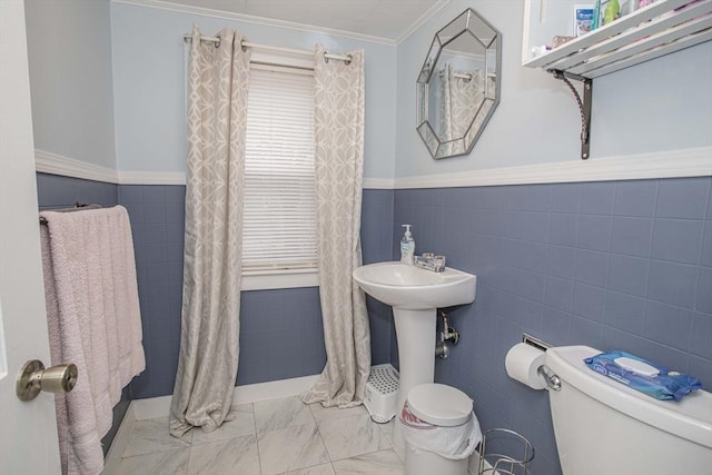 bathroom with toilet, marble finish floor, crown molding, and tile walls