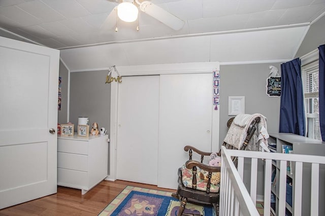 bedroom with a ceiling fan, lofted ceiling, a closet, and wood finished floors