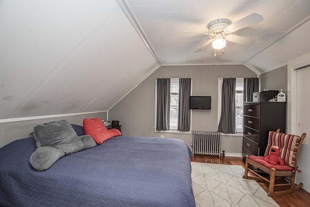 bedroom with vaulted ceiling, ceiling fan, radiator heating unit, and wood finished floors