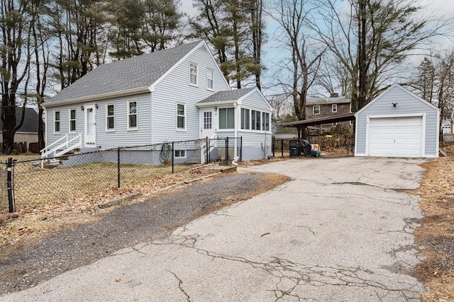 view of front of home with a fenced front yard, aphalt driveway, a detached garage, a shingled roof, and an outdoor structure