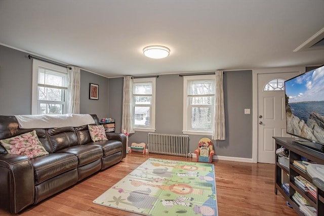 living room with radiator, crown molding, baseboards, and wood finished floors