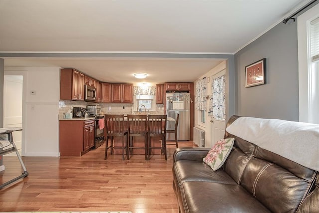 living area featuring light wood-style flooring and ornamental molding