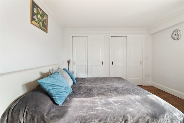 bedroom with multiple closets, crown molding, and dark hardwood / wood-style floors