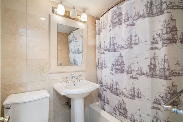 bathroom with tile walls, shower / bath combo with shower curtain, and toilet