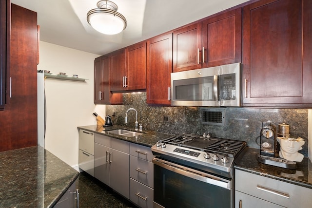 kitchen with dark stone countertops, stainless steel appliances, decorative backsplash, and sink