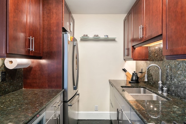 kitchen with sink, stainless steel fridge, tasteful backsplash, and dark stone countertops