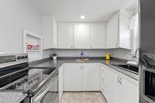 kitchen featuring dark countertops, electric stove, a sink, white cabinets, and recessed lighting