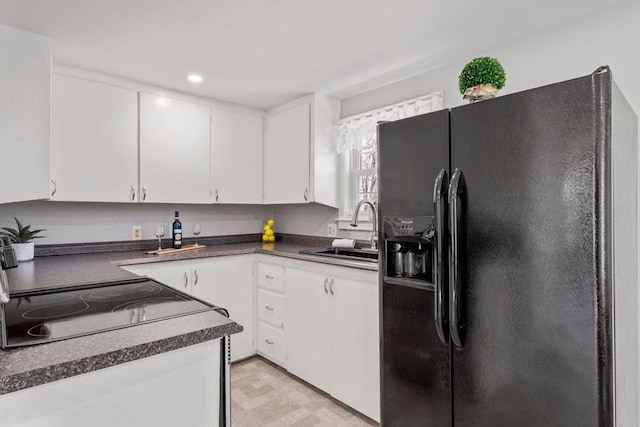 kitchen with dark countertops, a sink, black appliances, white cabinetry, and recessed lighting