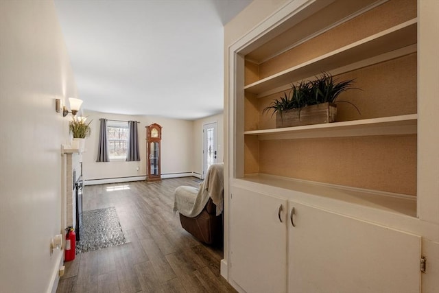 hallway with a baseboard heating unit, baseboards, and dark wood-style flooring