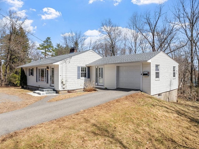ranch-style home featuring roof with shingles, a front lawn, a chimney, an attached garage, and aphalt driveway