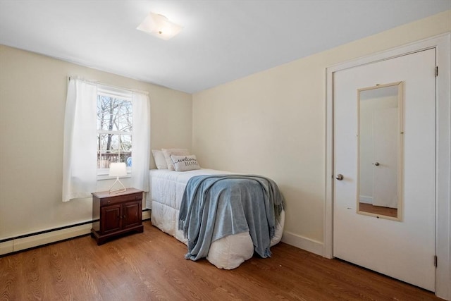 bedroom featuring light wood-style flooring, baseboards, and baseboard heating