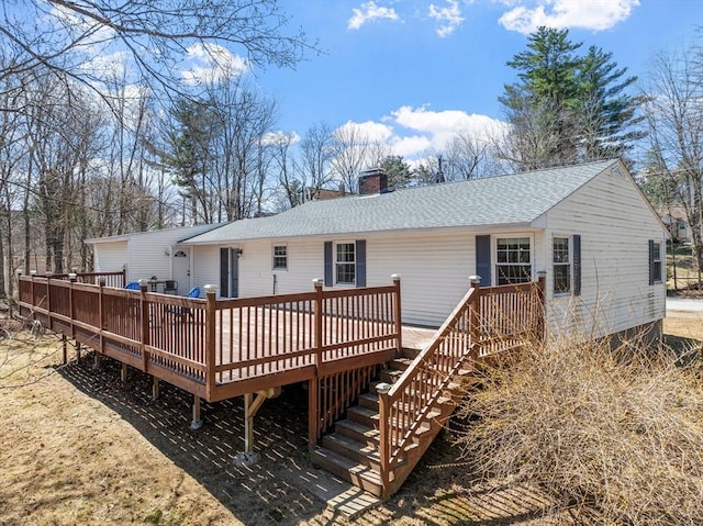 back of house featuring a wooden deck, a shingled roof, and a chimney
