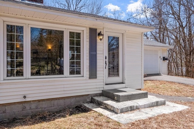 doorway to property featuring driveway, a shingled roof, and a garage