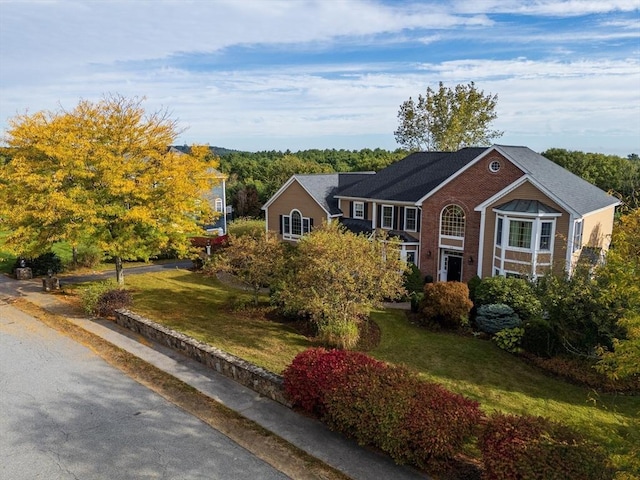 view of front facade with brick siding and a front lawn