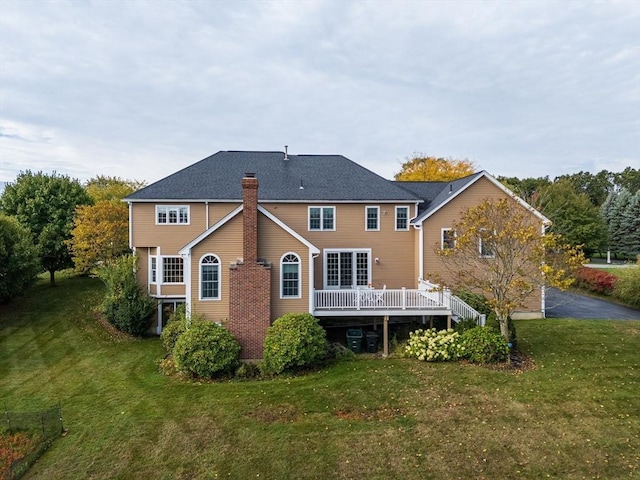 rear view of house with a lawn, a chimney, and a wooden deck