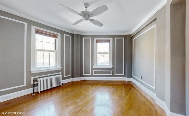 empty room featuring ceiling fan, crown molding, radiator heating unit, and wood-type flooring