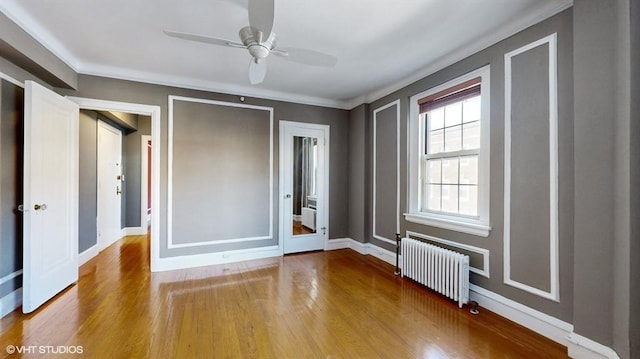 unfurnished bedroom featuring radiator, crown molding, light hardwood / wood-style flooring, and ceiling fan