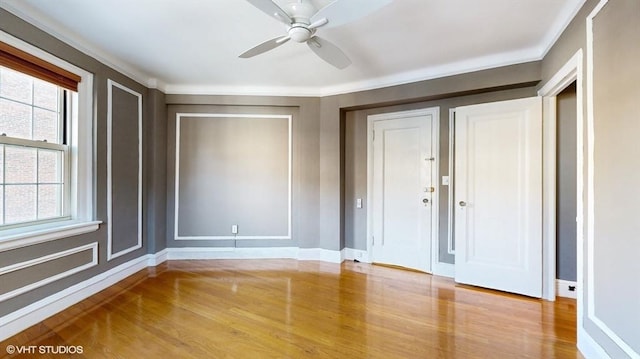 interior space with multiple windows, crown molding, ceiling fan, and light wood-type flooring