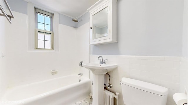 full bathroom with washtub / shower combination, toilet, sink, and tile walls