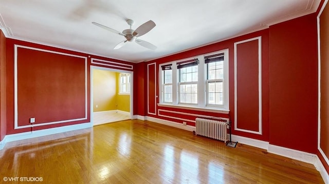 unfurnished room featuring wood-type flooring, ornamental molding, radiator heating unit, and ceiling fan