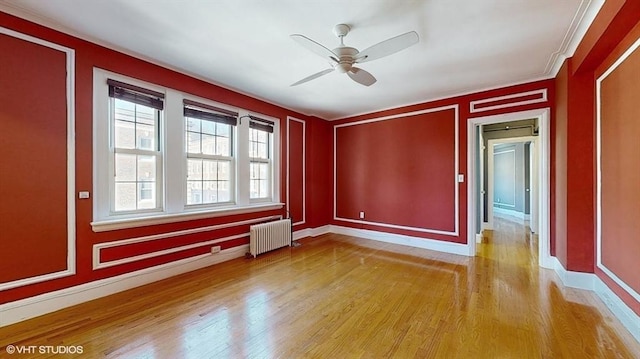 unfurnished room featuring radiator, ornamental molding, ceiling fan, and light wood-type flooring