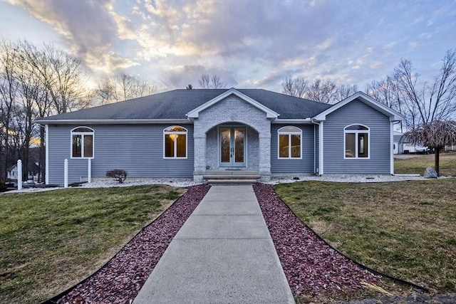 ranch-style home featuring a lawn and french doors