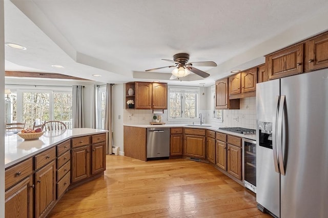 kitchen featuring wine cooler, light wood-style flooring, appliances with stainless steel finishes, brown cabinetry, and open shelves