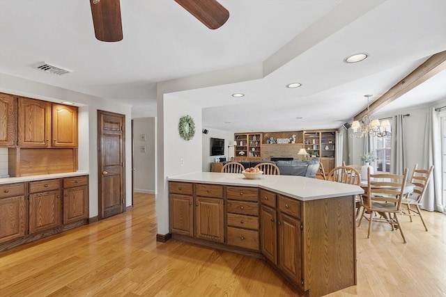 kitchen featuring light countertops, a brick fireplace, visible vents, and light wood-type flooring