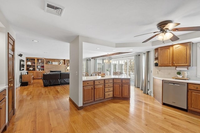 kitchen featuring visible vents, light wood finished floors, light countertops, stainless steel dishwasher, and backsplash