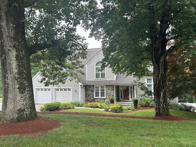 view of front of home featuring a garage, stone siding, driveway, and a front lawn