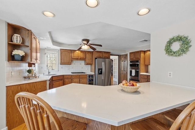 kitchen with a sink, a breakfast bar, appliances with stainless steel finishes, a peninsula, and open shelves