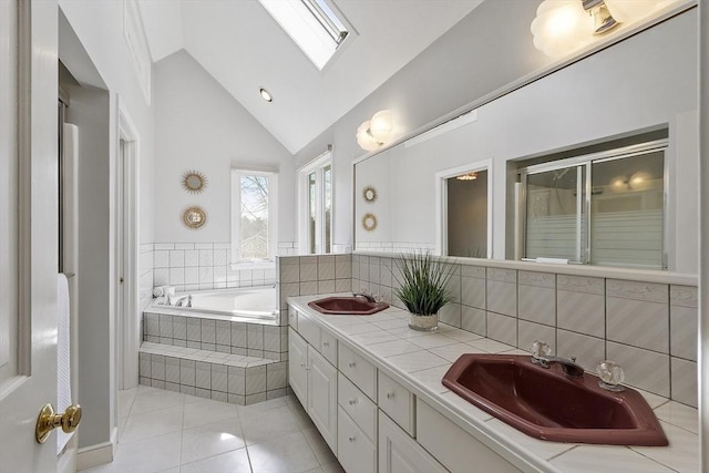 full bath featuring a sink, vaulted ceiling with skylight, a bath, and tile patterned flooring