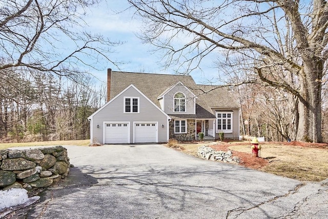 cape cod home with driveway and a shingled roof