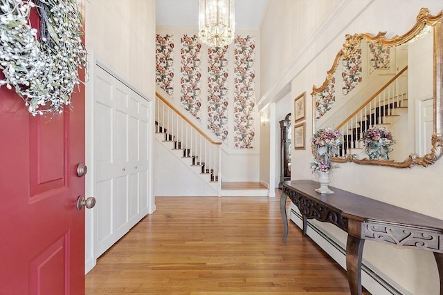 entryway featuring an inviting chandelier, a high ceiling, stairs, and light wood-style floors