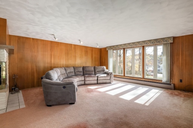 carpeted living room featuring baseboard heating, wooden walls, and a brick fireplace